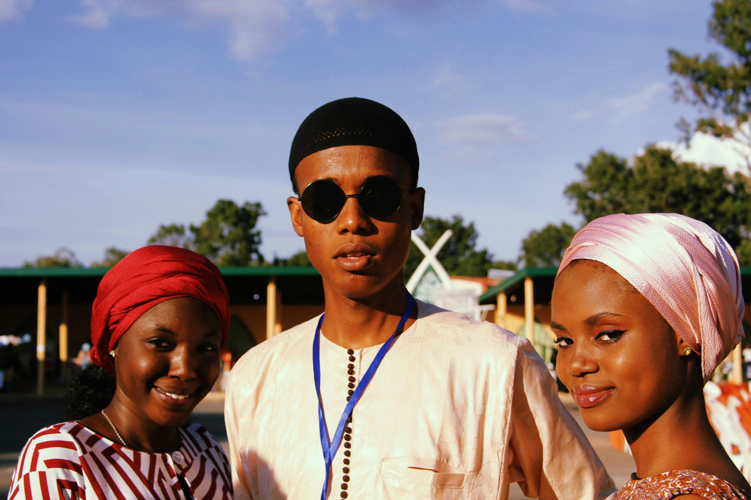 Group of friends smiling outdoors in traditional attire during a summer sunset.